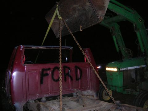 1996 Ford Bronco - A tractor is lifting a red Ford truck cab and chassis with chains and straps.