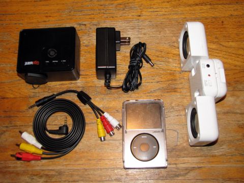 1984 Ford Bronco - Various electronic components, including a projector, iPod, and speakers, are laid out on a wooden table.