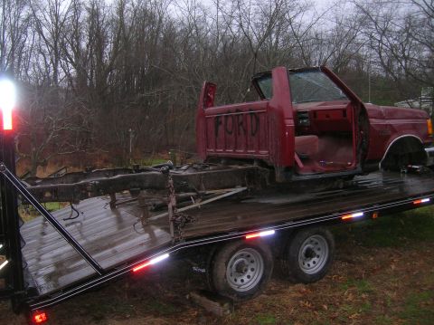 1996 Ford Bronco - A disassembled red Ford pickup truck is being transported on a flatbed trailer.
