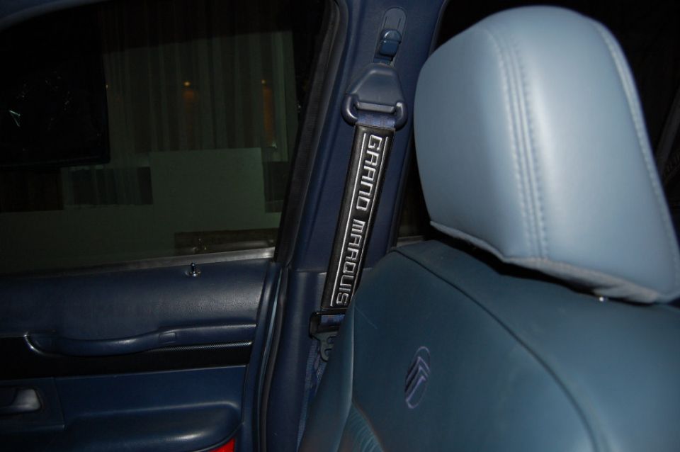Seat belt strap with "GRAND MARQUIS" text visible inside a car