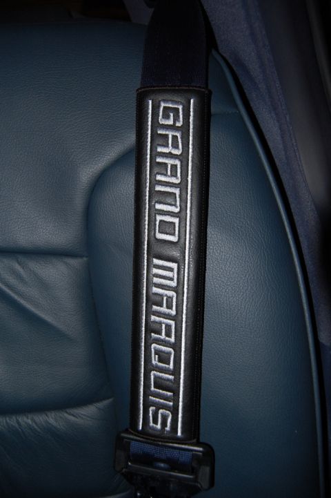 1985 Mercury Grand Marquis - A close-up of a seat belt shoulder pad embroidered with 'GRAND MARQUIS' is visible against a blue leather interior.