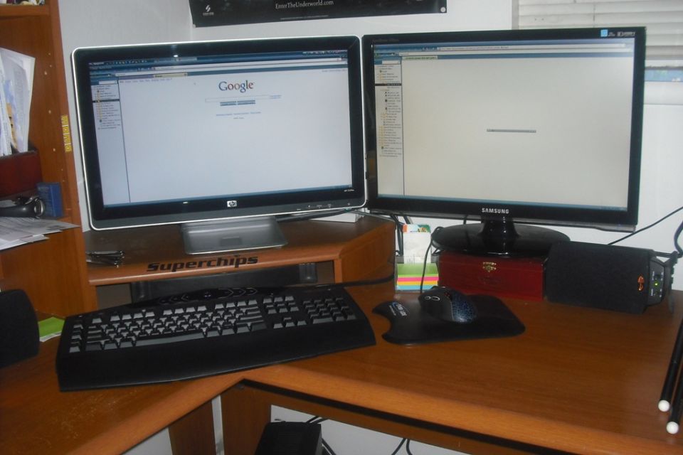 Computer desk with two monitors displaying web pages, a keyboard, mouse, and speakers