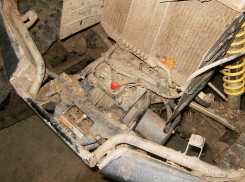 2000 Ford E350 - The engine bay of this off-road vehicle is heavily covered in mud, obscuring most details.