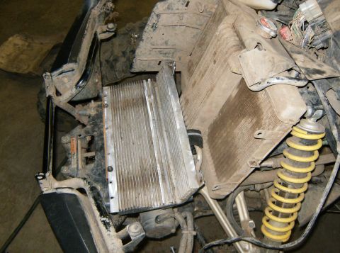 2000 Ford E350 - Close-up view of a vehicle's engine compartment, showing the radiator, a large heatsink, and a yellow shock absorber.