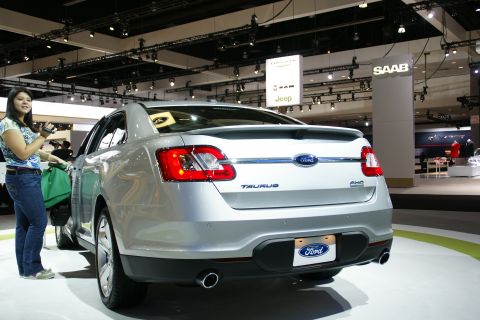 1993 Ford Taurus - A silver Ford Taurus is displayed at an auto show with a woman looking at it.