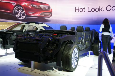 1993 Ford Taurus - A cutaway view of a car chassis with its engine and interior exposed, displayed at an auto show.