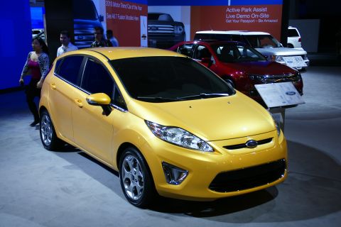 1993 Ford Taurus - A yellow Ford Fiesta is showcased at an auto show, with other Ford models in the background.