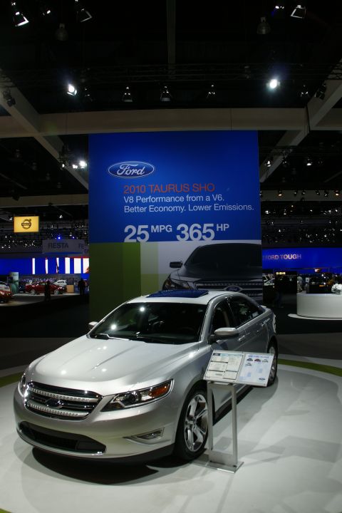 1993 Ford Taurus - A silver 2010 Ford Taurus SHO is displayed at an auto show with promotional signage.