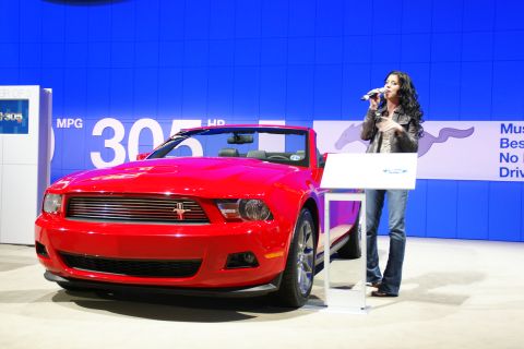 1993 Ford Taurus - A red convertible is displayed with a speaker at a podium in front of a blue backdrop.