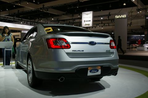 1993 Ford Taurus - Rear view of a silver sedan on display at an auto show, the Ford badge and Taurus nameplate.