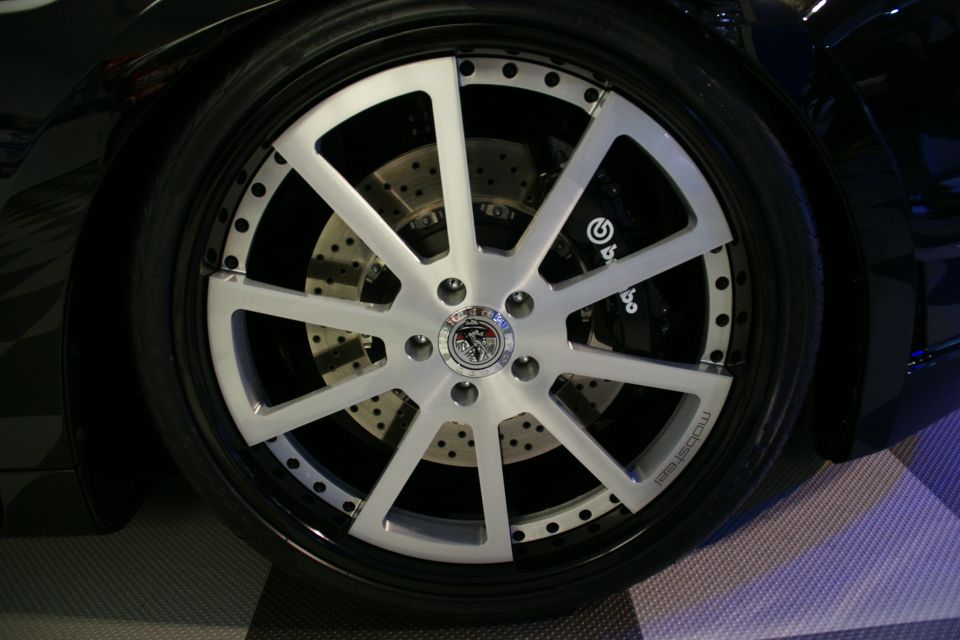 Close-up of a custom silver multi-spoke wheel with drilled rotors and Brembo brake calipers