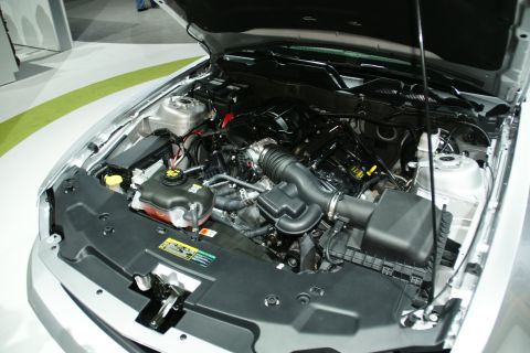 1993 Ford Taurus - The engine bay of a silver car is shown with the hood open, revealing the engine components and wiring.