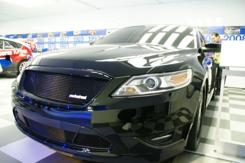 1993 Ford Taurus - Front view of a black sedan with a custom grille at an auto show display.