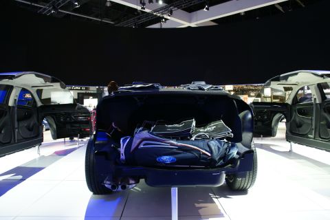 1993 Ford Taurus - Multiple Ford Taurus concept cars displayed at an auto show, with one open to reveal its interior and trunk contents.