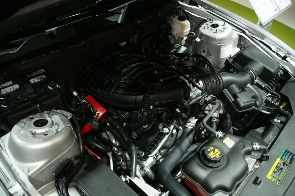 Engine bay with black plastic intake manifold, silver strut towers, and coolant reservoir