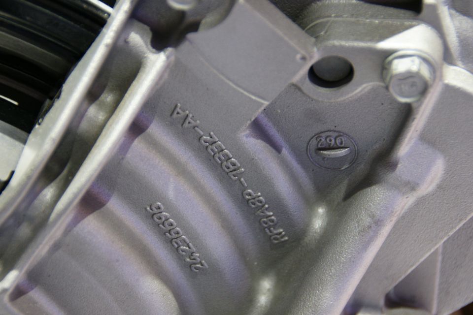Close-up of a metal engine part showing casting numbers RF8AB9-16532-AA and 26235695, and a circled 290