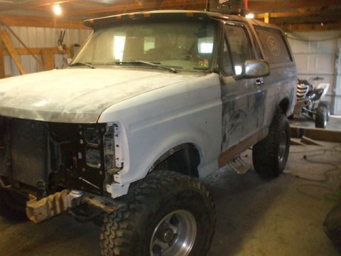 1995 Ford Bronco - This Ford Bronco is undergoing repairs in a garage, with its front end partially dismantled.