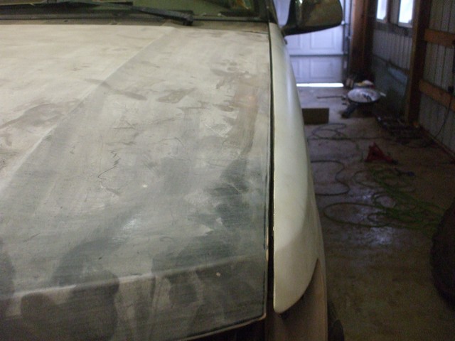 Truck hood and fender sanded to primer and filler inside a shop