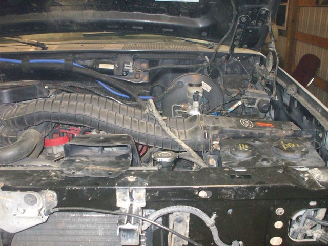 Engine bay front showing air intake tube, battery tray and master cylinder with grille removed