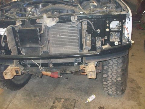 1995 Ford Bronco - The front end of a white Ford Bronco is disassembled, revealing the radiator and engine bay components.