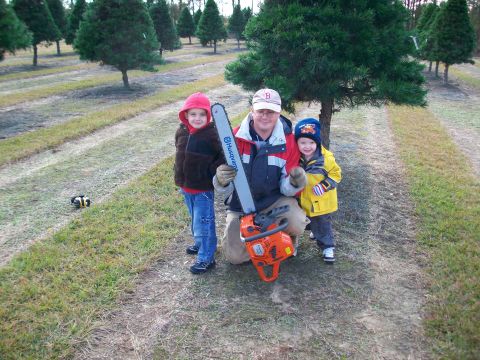 1983 Ford F-250 - Man and two children pose with a chainsaw in a Christmas tree farm.