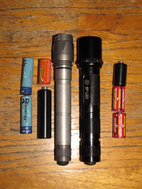1984 Ford Bronco - Two flashlights and various batteries are laid out on a wooden table.