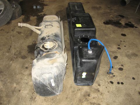 2005 Dodge 3500 - Two fuel tanks are shown side-by-side on a dirty concrete floor.