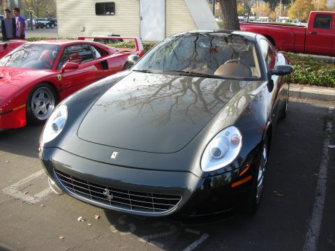 1998 Ford Crown Victoria - A dark gray Ferrari coupe is parked in a lot next to a red Ferrari F40.