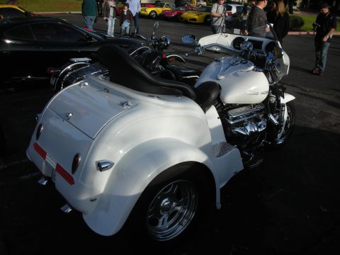 1998 Ford Crown Victoria - A white trike motorcycle is parked next to other vehicles.