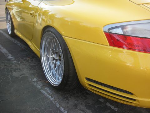 1998 Ford Crown Victoria - Close-up of a yellow sports car's rear section, showing custom wheels and a lowered stance.
