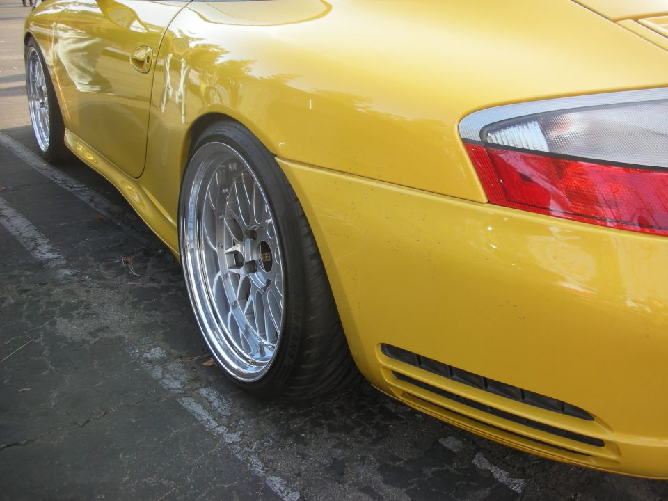 Yellow sports car rear quarter panel with aftermarket wheels and lowered suspension