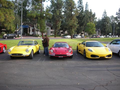 1998 Ford Crown Victoria - Three sports cars are parked in a lot, with a person standing between two of them.