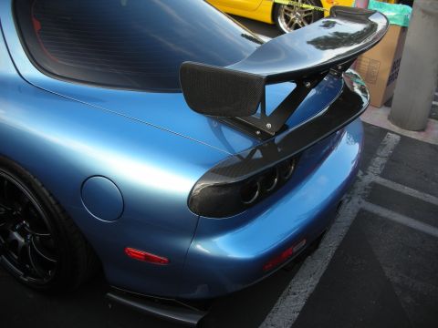 1998 Ford Crown Victoria - Blue sports car with a prominent rear spoiler, parked next to a yellow vehicle.