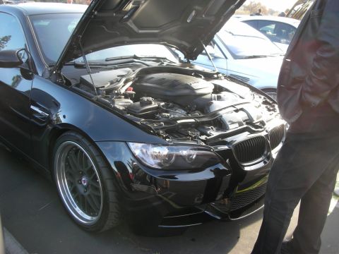 1998 Ford Crown Victoria - A black BMW M3 is parked with its hood open, revealing the engine compartment.