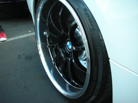1998 Ford Crown Victoria - A close-up shot focuses on a custom BMW wheel and tire, with a person's red shoe visible in the background.