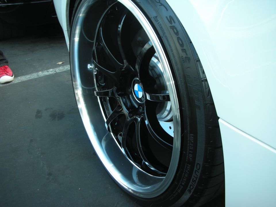Close-up of a shiny black BMW wheel with a blue and white logo on a white car