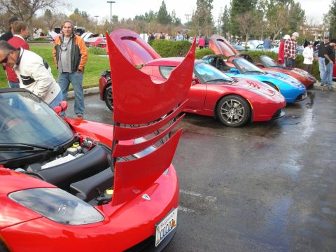 1998 Ford Crown Victoria - Several sports cars are lined up at an outdoor event, with one in the foreground having its hood open.