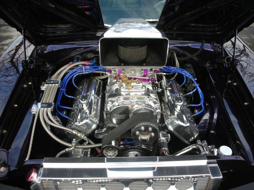 Engine bay with a supercharger, air intake, and chrome valve covers. A plate reads '392'