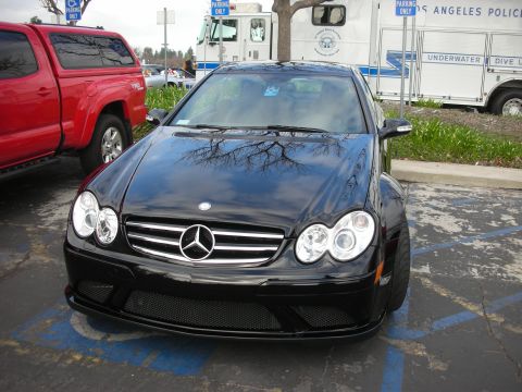 1998 Ford Crown Victoria - A black Mercedes-Benz coupe is parked in a handicapped spot, with a red truck and a Los Angeles Police Department vehicle in the background.