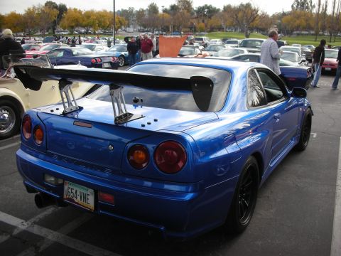 1998 Ford Crown Victoria - A blue Nissan Skyline GT-R is parked at an outdoor car show with many other vehicles in the background.