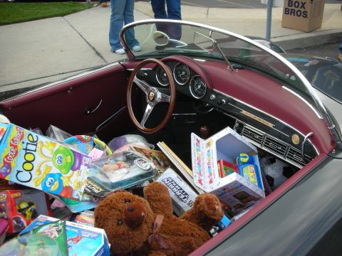 1998 Ford Crown Victoria - A vintage convertible's interior is overflowing with children's toys and games, obscuring the dashboard and seats.