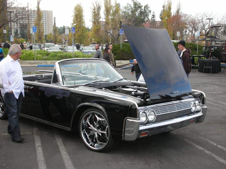 Black convertible with hood open, chrome grille, and custom wheels