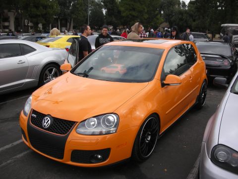 1998 Ford Crown Victoria - Orange Volkswagen Golf GTI with a GTI badge on the grille.