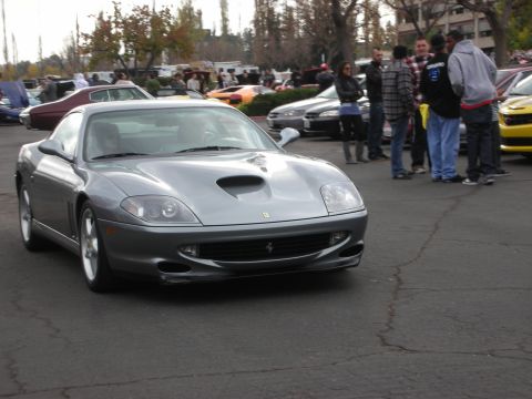 1998 Ford Crown Victoria - A silver Ferrari is the focus at a car show, with other vehicles and people in the background.