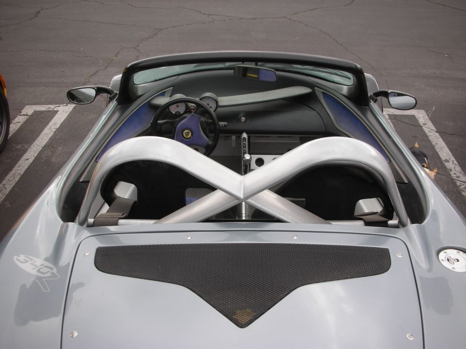 Silver sports car interior with a purple steering wheel, exposed roll cage, and a "340R" badge on the fender