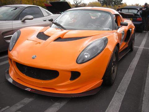 1998 Ford Crown Victoria - An orange Lotus Elise is parked in a lot, with another car visible behind it.