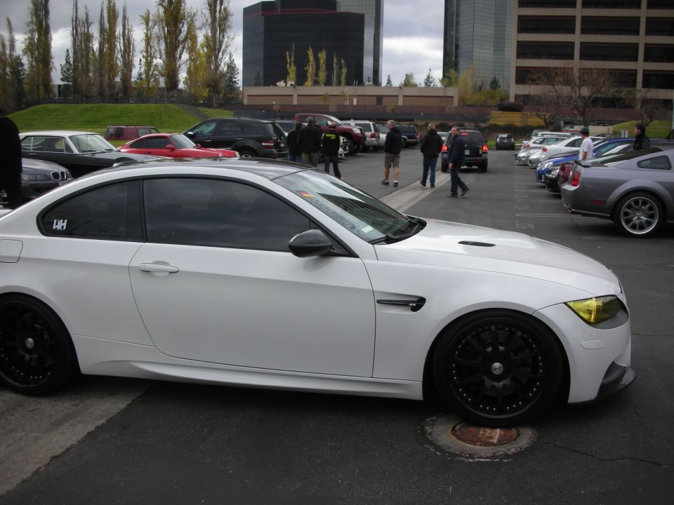 White coupe with black aftermarket wheels, tinted windows, and yellow tinted headlights parked in a lot