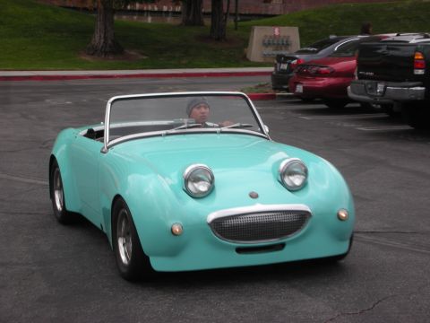 1998 Ford Crown Victoria - A teal convertible with a distinctive smiling grille drives in a parking lot.