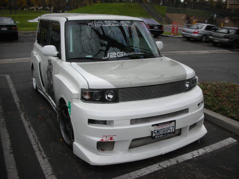1998 Ford Crown Victoria - Modified white Scion xB with custom body kit and graphics parked in a lot.