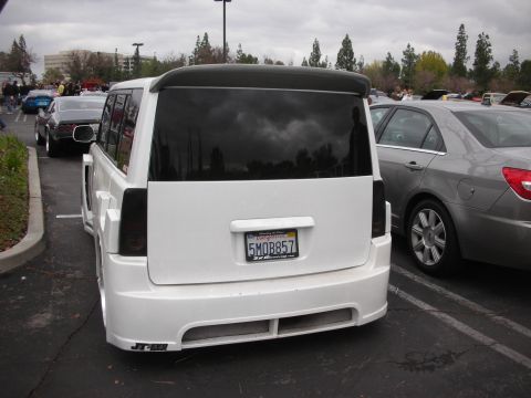 1998 Ford Crown Victoria - A white SUV with a custom body kit and spoiler is parked next to another car.
